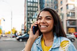 Mulher sorridente liga para linha telefónica do consumidor. A partir de 1 de novembro de 2021, existem novas regras para as linhas telefónicas dos fornecedores de bens e os prestadores de serviços.